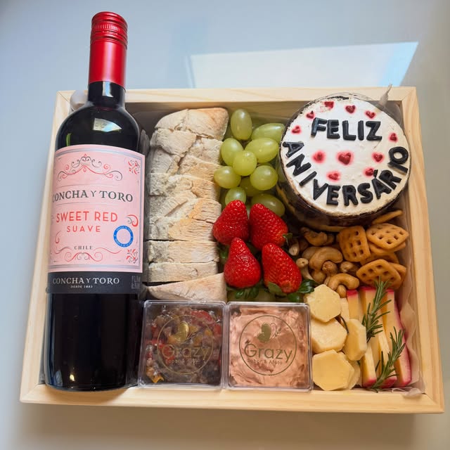 Tábua de aniversário com vinho, pães, frutas e bolo Feliz Aniversário